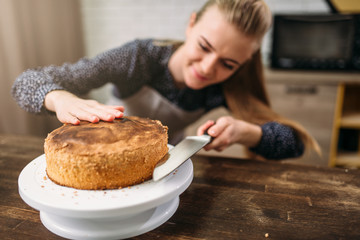 Woman cook cut baked cake with a knife