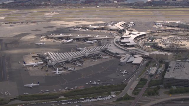 AERIAL, CLOSE UP: Flying above airplanes parked on apron waiting for passengers to board through jetway and start their traveling journey. Terminal building on New York Newark international airport
