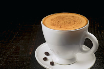 Cup of the bright coffee on the dark background