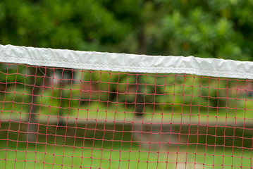 Close-up detail of a badminton net at a park with many trees, background defocus. Outdoors and...