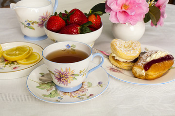 Cup of tea served in a vintage fine china tea cup with cream cakes.