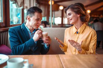 Man drinks a cocktail from straw against woman