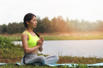 Fototapeta na wymiar Young asian woman in sportswear meditating on yoga mat