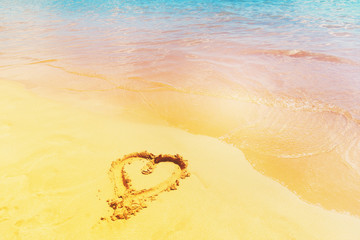 Heart draw in sand by tropical sea waterr, retro toned