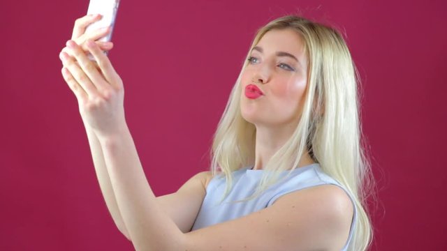 Blonde girl takes selfies of herself with smartphone