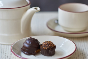 Chocolate petit four, cup and kettle of tea