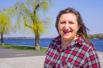 A portrait of a happy smiling woman on a background of river and willows