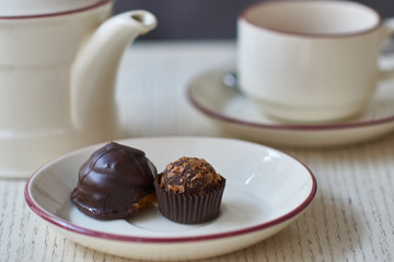 Chocolate petit four, cup and kettle of tea