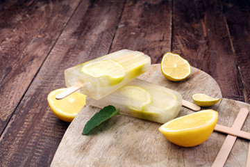 Healthy lemon popsicles with fresh lime slices on wooden background