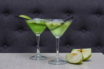 Two glasses of apple martini and apple slices on table in cafe