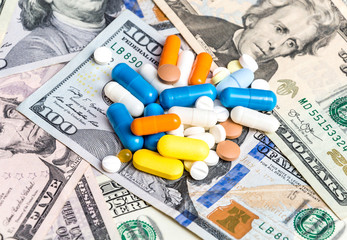 Heap of pills on the dollars background.