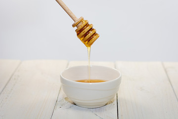 With a honey spoon a bowl is filled with flower honey