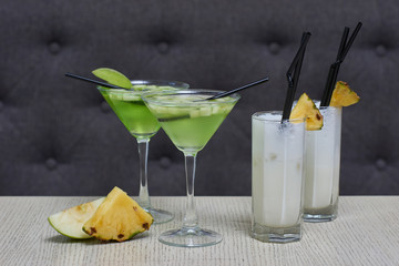 Apple martini and pina colada cocktails and apple and pineapple slices on table in cafe
