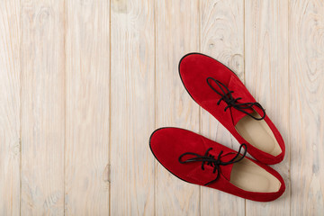 Red women's shoes oxfords on a light wooden background.