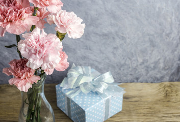 Mothers day concept of pink carnation flowers in clear bottle and gift box