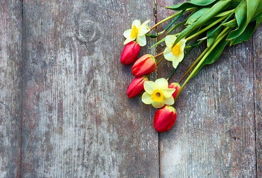 Bouquet of tulips and daffodils on a wood background