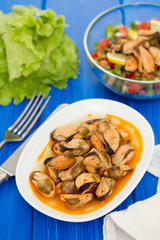 mussels in sauce on white dish on brown wooden background