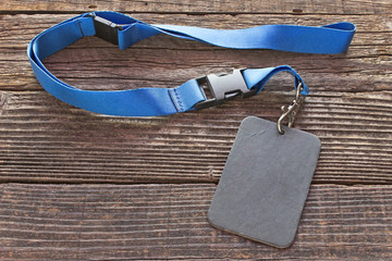 Blank ID card tag with blue ribbon on wooden background
