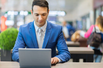 Businessman working on laptop computer at airport
