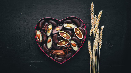 Chocolate box in the form of heart. On a black background Wooden. Top view.