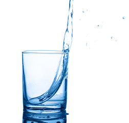 pouring blue water in transparent glass with drops isolated on white background, close up