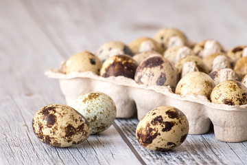 Quail eggs. Quail eggs in a cardboard container on a gray wooden table.