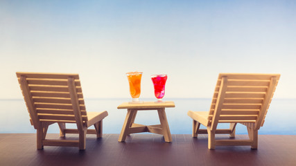 Wooden beach chairs or sun loungers with glass of oranges and strawberry juices on balcony and beautiful sea view on clear day in summer season