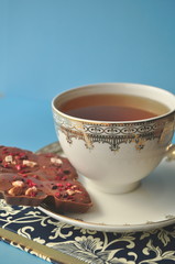 Cup of tea and chocolate on a notebook on blue background vertical