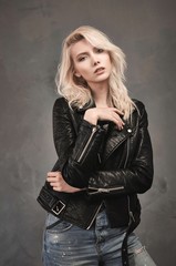 Fototapeta na wymiar Blonde girl dressed in blue jeans and a black leather jacket.