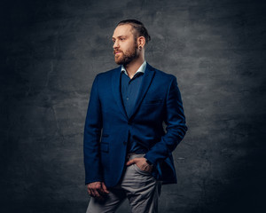 Elegant bearded male with piercing in a nose, dressed in a blue jacket.