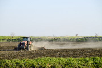 Fototapeta premium A tractor with a plow lays the soil. Soil cultivation on the fie