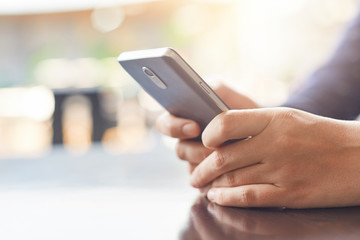 Cropped shot of woman`s hands holding mobile phone checking her e-mail online in cafe using high-speed internet connection.Technology and communication concept.