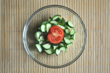 preparing vegetarian salad, a bowl of vegetables tomato and cucumber, top view