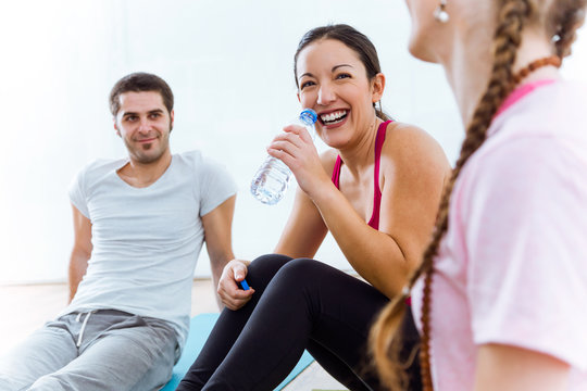 Group of people relaxing on yoga mat and talking after workout session.