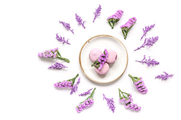 macaroons and flowers for light breakfast on white desk background top view