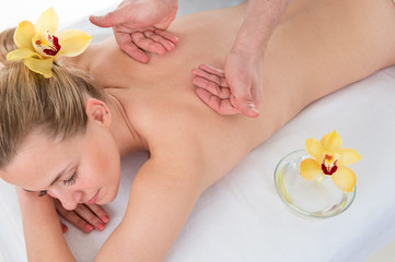 Woman getting massaging treatment over white background in spa