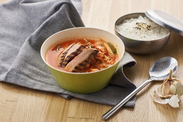 Korean cuisine. Spicy kimchi soup served in a bowl standing on wooden table.