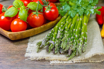 varied vegetables pepper, asparagus, onions, cabbage and olive oil on a wooden background