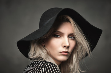 A tall girl dressed in black blouse with white stripes and black pants.