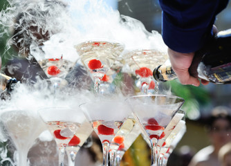 Pyramid or fountain made of champagne glasses with cherry and steam from dry ice