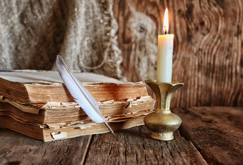 feather and book novel close to the a candle