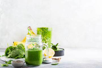 Healthy green smoothie with spinach, banana, lemon, apple and chia seeds in glass jar and ingredients. Detox, diet, healthy, vegetarian food concept with copy space.