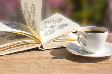 Coffee cup with open book over spring garden