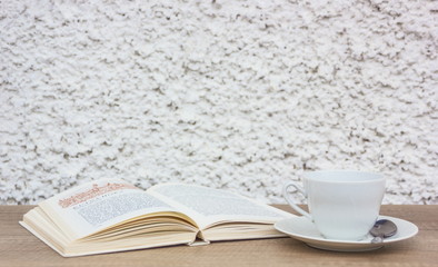 white cup of the coffee and vintage book