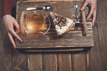 hands with tea and cake on wooden desk