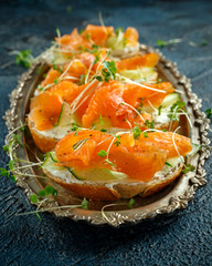 Smoked salmon bruschettas with soft cheese and cucumber shavings on a vitage plate