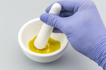 Pharmacist preparing formula master for cosmetic in white mortar on a white background