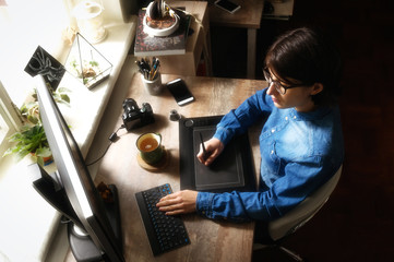 Designer's workplace, top view. Girl designer at work. The photo is made in warm colors with soft lighting and saturated colors.