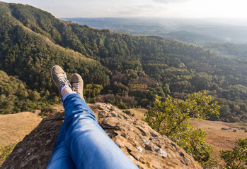 Ноги девушки на краю обрыва на камне на фоне гор и леса. В Кисловодском национальном курортном парке. Россия, Ставропольский край, Кисловодск © pelatophoto