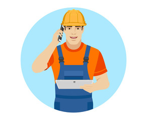 Builder holding digital tablet and talking on the mobile phone